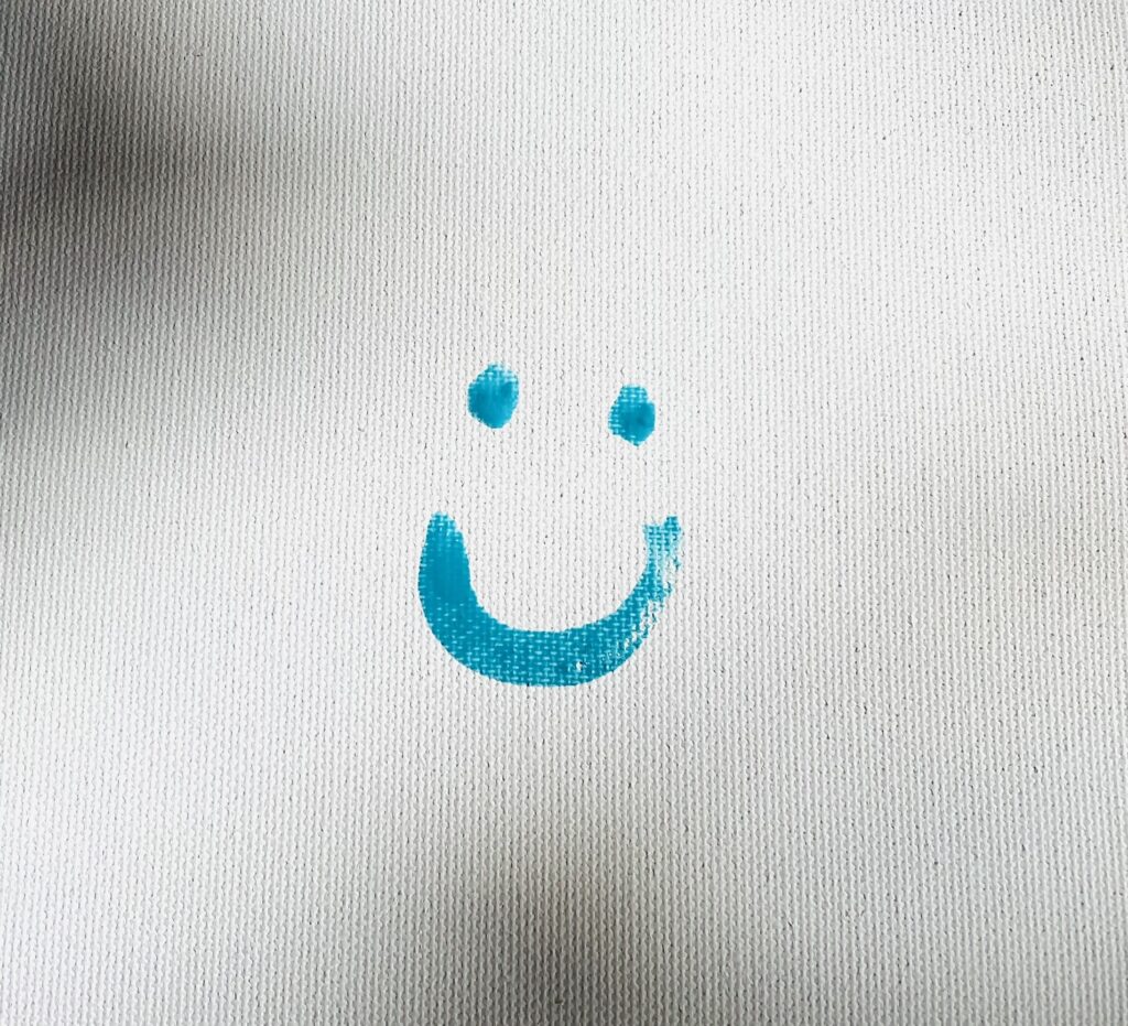 Painted blue smiley face on white canvas