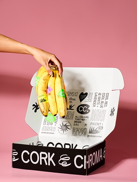 A hand putting a bunch of bananas in Cork & Chroma's Capsule Colleciton 001 Gift Box