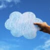 A hand holding Cork & Chroma's Limited Edition acrylic Cloud Palette in Nimbus (blue sparkle) up to the sky