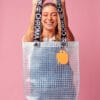 Model laughing and holding PVC&C Tote Bag by Cork & Chroma with neon orange Smol Palette Keychain