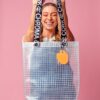 Model laughing and holding PVC&C Tote Bag by Cork & Chroma with neon orange Smol Palette Keychain