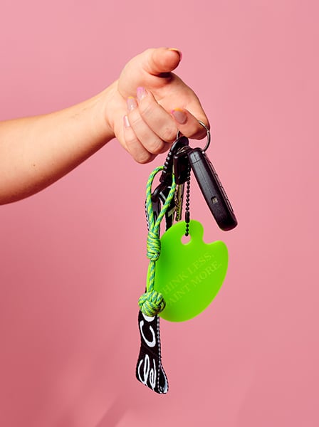 A hand holding the Smol Palette Keychain by Cork & Chroma, on a set of keys