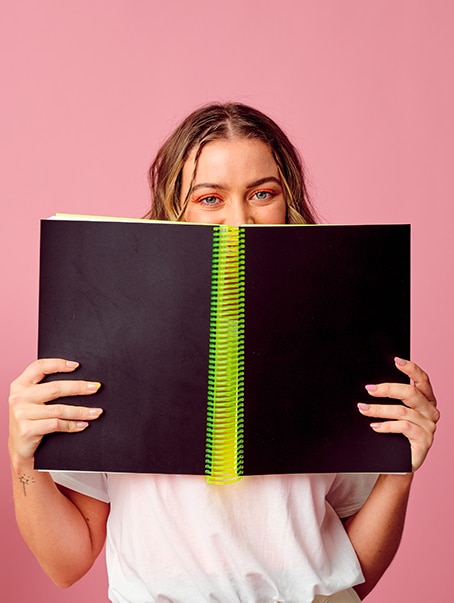 Model peeking over the top of Limited Edition "Mountain Dew" Thick Creative Diary by Cork & Chroma