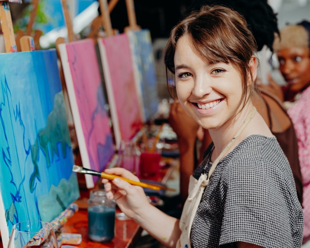 Guest looking at camera with paintbrush in hand at Cork & Chroma